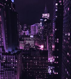 the city skyline is lit up at night with purple lights and skyscrapers in the background