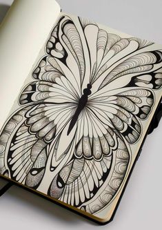 an open notebook with a drawing of a butterfly on the cover and black lines in the middle