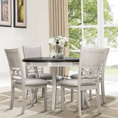 a dining table with four chairs and a vase on top of it in front of a window