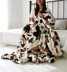 a woman sitting on top of a bed under a blanket