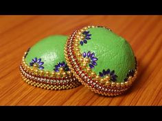 two green and gold decorated eggs sitting on top of a wooden table