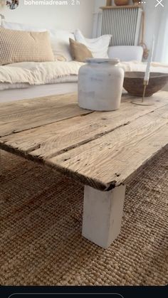 a wooden table sitting on top of a rug next to a white couch in a living room