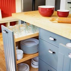 an open cabinet in the middle of a kitchen with plates and bowls on top of it