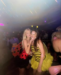 two women dressed up as bee and ladybug kissing each other on the dance floor