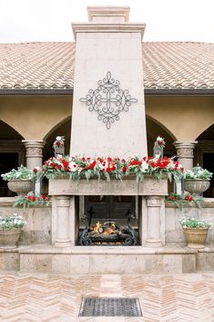 an outdoor fireplace decorated with red and white flowers