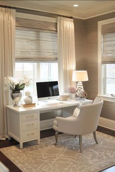 a white desk with a computer on top of it in front of two large windows