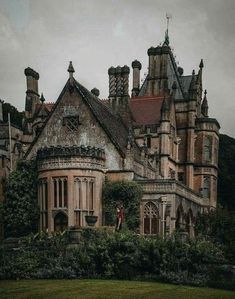 an old castle like building with ivy growing on the roof and windows, surrounded by greenery