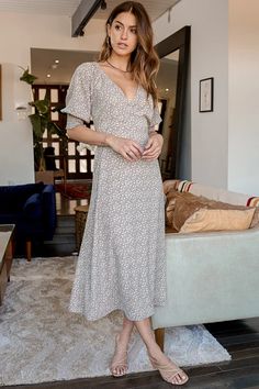 a woman standing in front of a couch wearing a dress with floral print on it