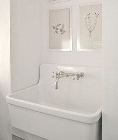 a white sink in a bathroom next to a toilet and shower stall with pictures on the wall above it