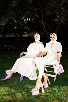 two women dressed in white sitting on lawn chairs, one wearing sunglasses and the other holding shopping bags