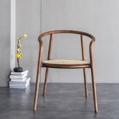 a wooden chair sitting next to a stack of books and a vase with yellow flowers