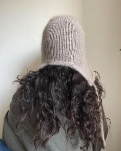 the back of a woman's head with curly hair and a knitted hat