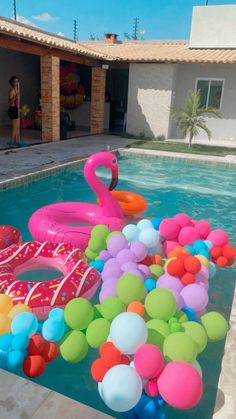 an inflatable flamingo floating on top of a swimming pool filled with balloons