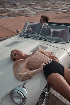 a woman laying on the hood of a white car