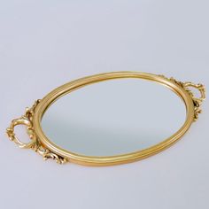 a gold plated mirror on a white surface with an ornate design around the edge