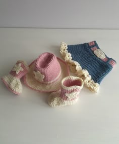 a crocheted hat, booties and diaper sit on a table