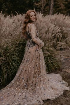 a woman standing in front of some tall grass wearing a dress with stars on it