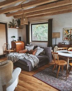 a living room filled with furniture next to a wooden floor and window covered in curtains