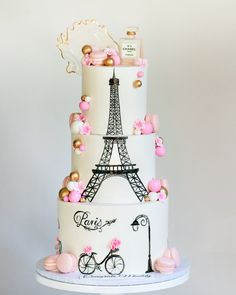 a three tiered cake with the eiffel tower on it's side