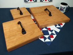 three wooden cutting boards sitting on top of a blue table cloth next to a mug