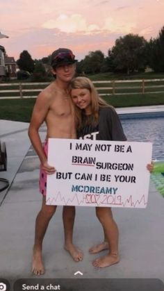 a man and woman standing in front of a swimming pool holding a sign that says i may not be a brain surgeon but i can be your mcdreamiy