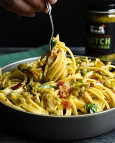 a person is spooning some food out of a bowl with pasta and broccoli