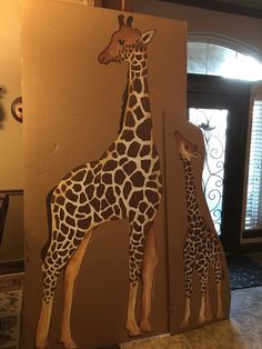 a giraffe and her baby standing next to each other in front of a door