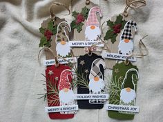 christmas tags are hanging from twine with holly and mist on them, all decorated in different designs