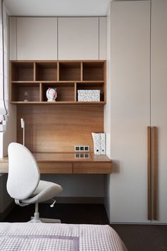 a white chair sitting in front of a desk with a book shelf on top of it