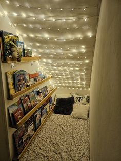 a room with some bookshelves and lights on the ceiling above it, as well as a bed