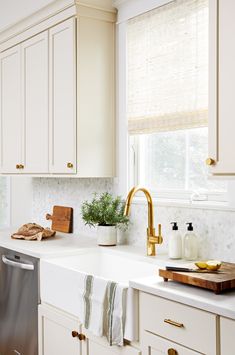 a kitchen with white cabinets and gold faucet pulls on the handles, along with a dishwasher