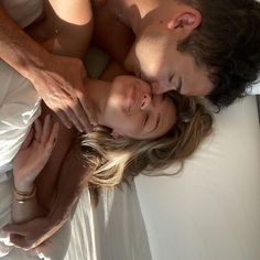 a man and woman laying on top of a bed next to each other with their eyes closed