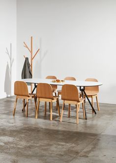 a dining table with four chairs and a vase on the wall in an empty room