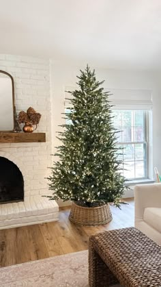 a living room with a christmas tree next to a fire place and a couch in front of the fireplace