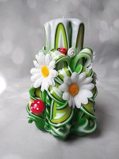 a green vase with white flowers and ladybugs on it