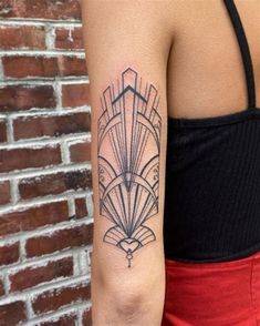 a woman with a black and white tattoo on her arm, standing in front of a brick wall