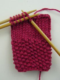 two knitting needles are next to a red knitted object