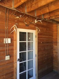 the inside of a wooden cabin with glass doors and wires hanging from the ceiling over the door