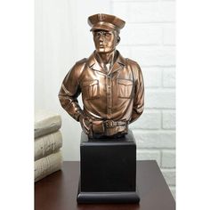 a bronze busturine of a man in uniform on a wooden table next to a stack of books