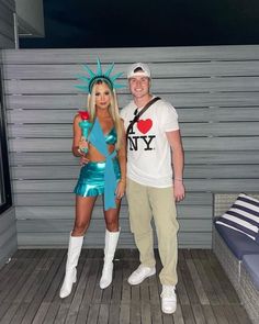 a man and woman dressed up as the statue of liberty pose for a photo in front of a wall