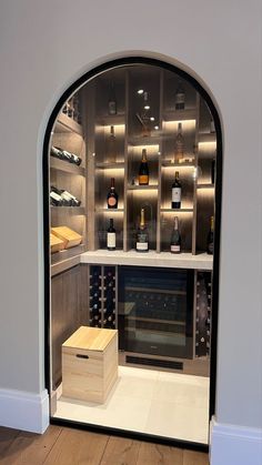 an arched doorway leads to a wine cellar with bottles on the shelves, and a wooden crate under it