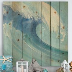 an ocean themed wall hanging over a table with seashells, candles and other items