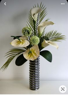 a vase filled with white flowers and green leaves