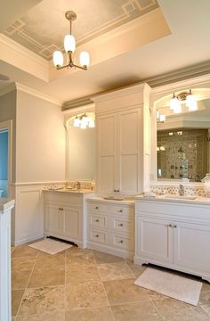 a large bathroom with white cabinets and marble counter tops