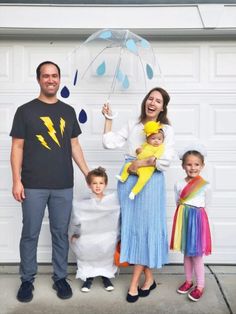 the family is posing for a photo in front of their garage door with an umbrella