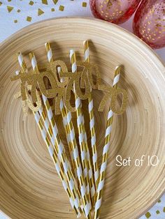 paper straws with gold and white stripes are on a plate next to pink glasses