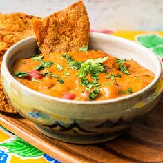 a bowl of salsa with tortilla chips on a wooden tray next to it