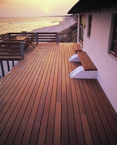 a wooden deck overlooking the ocean at sunset