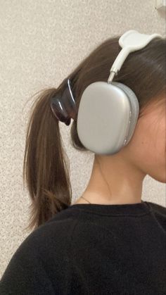 a woman with headphones on her ears is looking down at the wall behind her