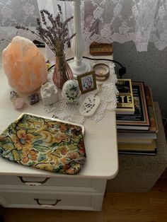 a white table topped with a vase filled with flowers next to a lamp and other items